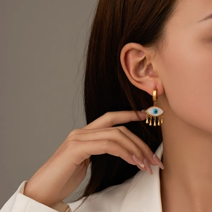 Detailed shot of golden hoop earrings featuring blue evil eye charms and fine tassels
