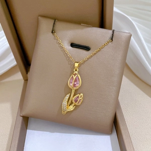Detail of a gold tulip pendant with pink gemstones resting on a beige cushion