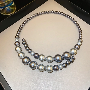 Detail of grey gradient faux pearl necklace with silver spacers on a textured tray