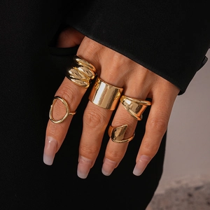 Close-up of five-piece gold chunky geometric rings worn on model against black suit