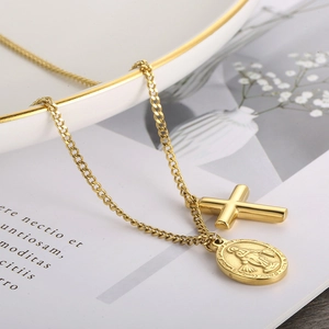Detail of gold titanium steel cross and oval coin religious pendant on a ceramic dish