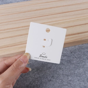Close-up of white jewelry display card with Smile logo and hanging hole for accessories