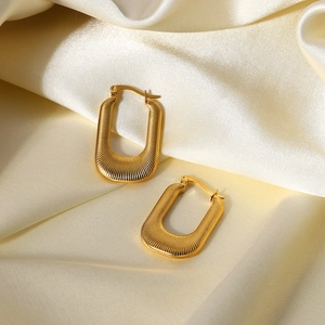 Elegant gold U-shaped textured earrings on white silk fabric with soft lighting