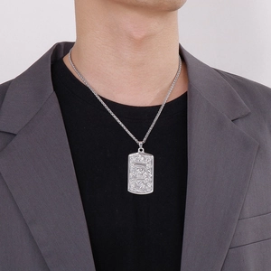 Close-up of a silver dragon pendant necklace worn by a man in a grey suit jacket