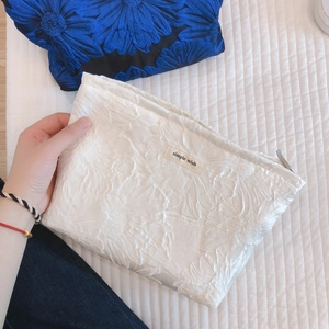 Floral jacquard canvas makeup bag with zipper and logo label shown in hand