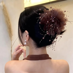 Pince à cheveux fleur marron foncé avec perles et pompons sur une coiffure élégante