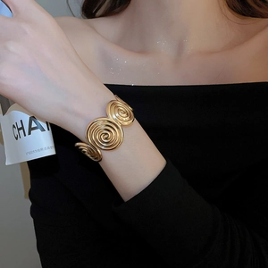 Detailed macro of gold wide open cuff bracelet featuring three 3D spiral textured disks