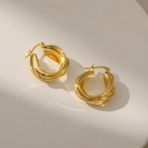 Macro detail of high-polished 18K gold-plated twisted geometric hoop earrings
