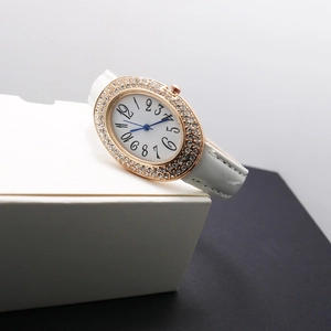 Montre quartz ovale pour femme avec lunette en strass rose doré et bracelet en cuir blanc