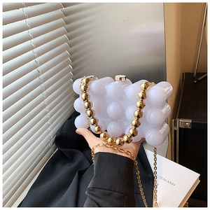 Detailed view of white bubble acrylic clutch with gold bead handle and crossbody chain