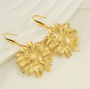 Detail of gold sunflower earrings with hammered metal texture on white fabric