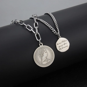 Détail de colliers superposés en argent avec pendentifs pièces sur un support noir