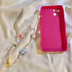 Pink wavy silicone phone case with colorful tulip flower beaded lanyard on cream fabric