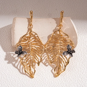 Elegant gold hollow leaf earrings with small silver butterfly accents on stone base