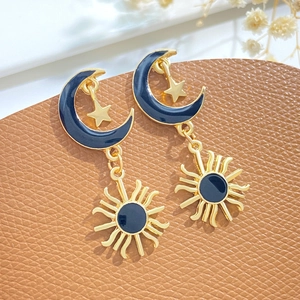 Detail of vintage gold-tone sun and moon enamel earrings on brown leather background