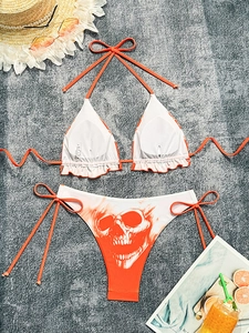 Flat lay of an orange and white skull flame bikini set with beach vacation accessories