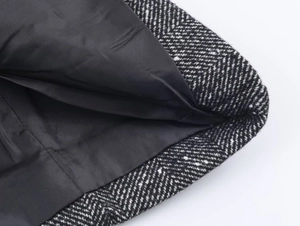 Close-up of black and white herringbone wool fabric with black inner lining stitching
