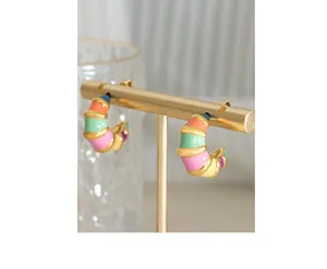 Macro view of C-shaped hoop earrings with colorful enamel stripes on a gold metal base