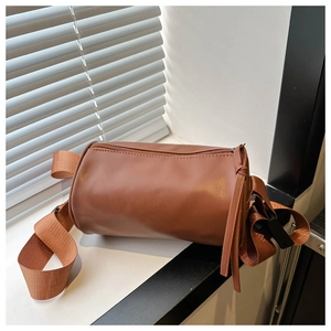 Dettaglio di una borsa a cilindro marrone con tracolla larga e nappa decorativa in stile
