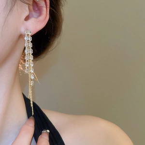 Close-up of elegant gold tassel earrings with clear crystals on a model side profile