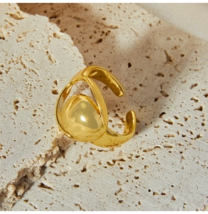 Detailed close-up of a gold-plated geometric ring with a spherical design on stone surface