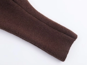 Detailed macro view of the dark brown knitted sleeve cuff with soft wool texture