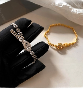 Detail of gold and silver chain bracelets with pave zircon links on a white surface