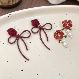 Close-up of velvet rose earrings with ribbon bows and drop pearls on a vintage tray