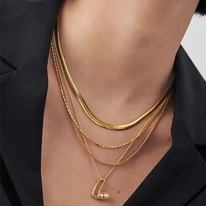 Détail d'un collier doré à plusieurs rangs avec pendentif géométrique et perles