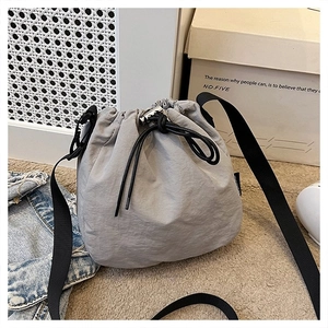 Detailed view of grey nylon drawstring bucket bag with black adjustable strap in casual setting