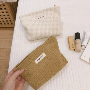 Detailed waffle texture of cream and yellow canvas zipper makeup bags with simple wish label