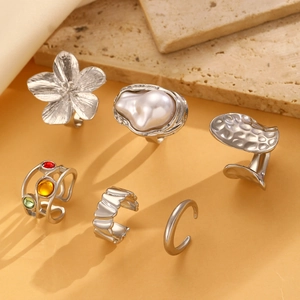 Detail of baroque pearl and floral silver ring set on a beige stone surface