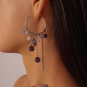 Detail of silver hoop earrings with purple crystal beads and long chain tassels on a model