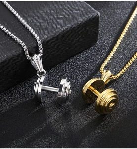 Close-up of gold and silver dumbbell pendants on chains over a black gift box