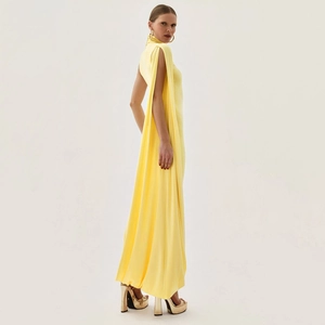 Detail of elegant yellow high-neck gown featuring dramatic cape-style floor-length slit sleeves