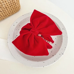 Detail of red velvet bow hair claw clip on a decorative white ceramic plate