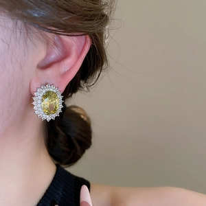 Detailed view of silver zircon oval stud earrings on model with yellow gemstone accent