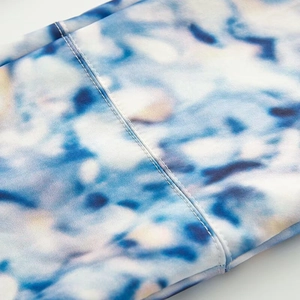 Detailed close-up of premium stitching and blue watercolor print on women's winter ski jacket