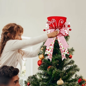 Red Christmas tree topper hat with festive ribbons and lollipops on a green pine tree