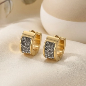 Detail of gold crystal-paved hoop earrings displayed on premium beige silk fabric
