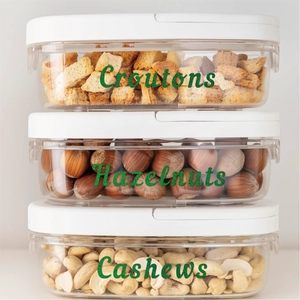 Stackable food storage containers with white lids and green glitter labels on clear plastic