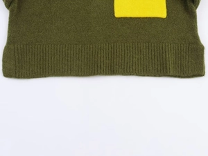Detail of dark green knit sweater rib cuff with yellow rectangular intarsia design