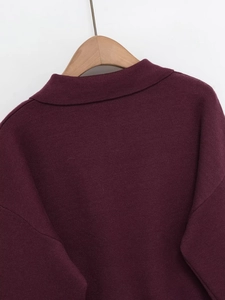 Detail of burgundy polo knit collar and shoulder texture on a wooden hanger