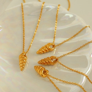 Minimalist gold spiral conch shell pendant necklaces on an iridescent shell tray
