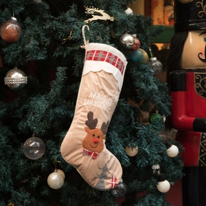 Christmas stocking with reindeer embroidery hanging on a festive decorated tree