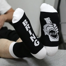 Detailed view of novelty cotton socks featuring Bring Beer text and graphic on model