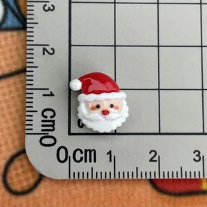 Macro view of a 1cm mini resin Santa Claus charm on a measuring scale for nail art