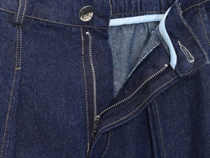 Detailed macro view of metal zipper and vintage silver button on dark blue denim fabric