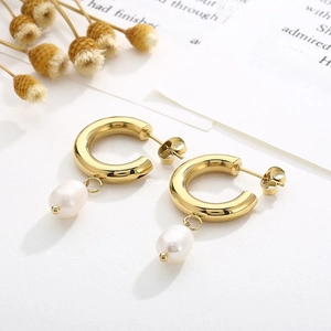 Détail de boucles d'oreilles créoles plaquées or 18K avec perles blanches en goutte