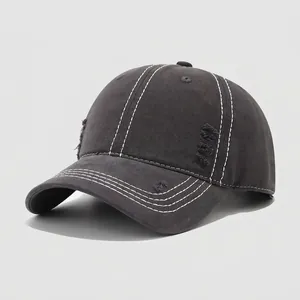 Detalle de gorra de béisbol de algodón gris oscuro con costuras blancas y agujeros desgastados